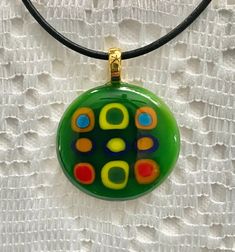 A unique, kiln fused glass pendant, custom designed for you, with floating vibrant, multi-colored blocks stacked in a variety of colorful rows encircled by the dark green edges upon a light green base.  A 16 inch black leather cord necklace with a 1.5 inch chain extension & nickel-free, silver-plated chain & clasp is included.  A fashionable & stylish, chic & modern mosaic glass necklace.  Dress up blue jeans, relax in loungewear or accent evening attire.  Created & handcrafted in a home worksho Glass Necklace Pendant, Modern Mosaic, Fused Glass Necklace, Modern Mosaics, Leather Cord Necklace, Jean Bleu, Necklace Dress, Leather Corded Necklace, Fused Glass Pendant