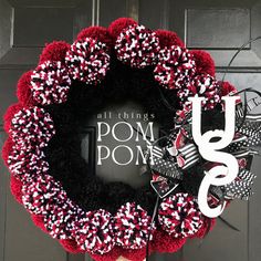 a red and black wreath with the words pom poms on it in front of a door