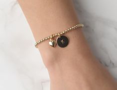 "This popular beaded bracelet comes with a sweet heart charm and, if desired, discs with your initials engraved on them. Perfect for gifting, the bracelet is made of all quality 14k Gold filled material. ● ITEM DETAILS ● ◦ 14K gold filled 3mm beads ◦ 14K gold filled 13mm initial disc ◦ 14K gold filled heart ◦ Made with nylon/stretch cord ● HOW TO ORDER ● Please select: 1. select the number of discs 2. select the size of your bracelet. 3. leave a message to the \"note to seller\" at checkout with Dainty Bracelet With Heart Charm And Round Beads, Gold Beaded Bracelets With Heart Charm For Friendship, Gold Name Bracelet With Heart Beads For Friendship, Friendship Charm Bracelet With Heart Charm And Round Beads, Gold Heart Bracelet With Letter Beads, Personalized Gold Bracelet, Gold Bead Bracelet, Gold Heart Bracelet, Signature Bracelet