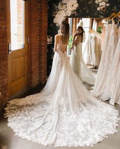 a woman standing in front of a mirror wearing a wedding dress