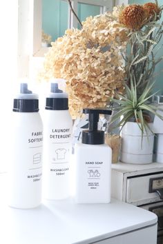 three bottles are sitting on a counter next to a plant and other items in front of a mirror