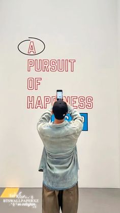 a man taking a photo of a sign with his cell phone in front of him