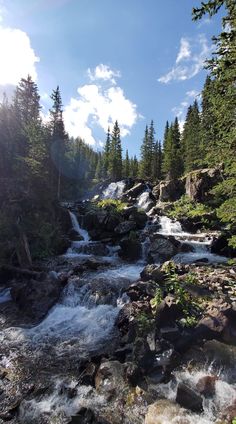 the sun shines on a small waterfall in the woods near some rocks and trees