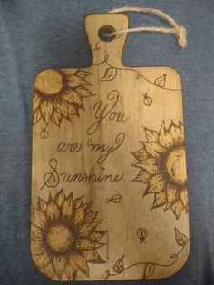 a wooden cutting board with sunflowers on it and the words you are my sunshine