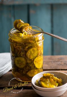 a jar filled with pickles sitting on top of a table next to a spoon