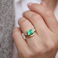 a woman's hand with a gold ring and green stone in the middle, on top of her finger