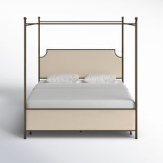 a white bed with a beige headboard and two pillows on top of the bed