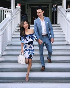 a man and woman are walking down the stairs together in front of a building with white railings