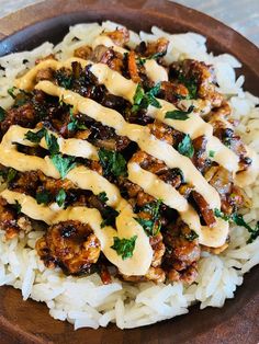 a bowl filled with rice and meat covered in sauce