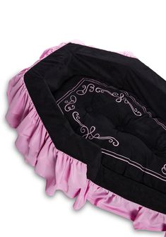 a black and pink dog bed with ruffled edges