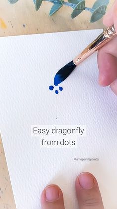 a person holding a paintbrush over a piece of paper with the words easy dragonfly from dots