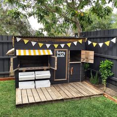 an outdoor bbq with yellow and white buntings on the roof is shown