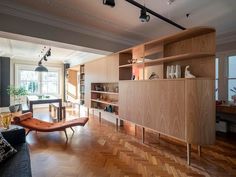 a living room filled with furniture next to a wooden floor covered in bookshelves