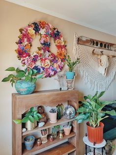 a living room filled with lots of plants and decor on top of a wooden shelf