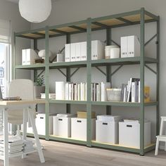 a white chair sitting in front of a wooden book shelf filled with books and boxes