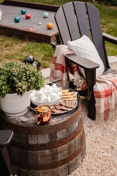 an outdoor table with food on it next to a chair and potted plant in the background