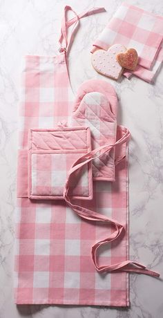 pink gingham kitchen towels and oven mitts laid out on a marble surface