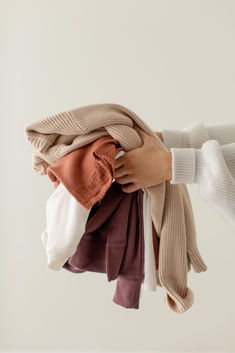 a woman holding several different colored scarves in her hands, all folded up and untied