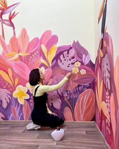 a woman is painting a mural on the wall in front of flowers and birds,