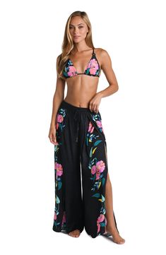 This cover up features a bold floral print with large pink flowers accented by dark and light green leaves. The pattern is set against a dark background, emphasizing the vibrant colors of the flowers and foliage. Perfect for pulling on post dip, the palazzo-style beach pants are perfect as a swimsuit coverup but can also be worn with a tank or cami for a no-fuss pulled together look. An adjustable waist tie finished with gold and black enamel charms offers a comfortable fit. [split] Details Beac Bohemian Floral Print Beach Bottoms, Bohemian Floral Beach Bottoms, Bohemian Floral Print Bottoms For Beach Season, Bohemian Beach Season Floral Bottoms, Bohemian Floral Print Pants For Beach Season, Bohemian Pants With Floral Print For Beach Season, Summer Floral Print Tie-side Bottoms, Floral Print Tie-side Bottoms For Beach, Pink Floral Print Beach Pants