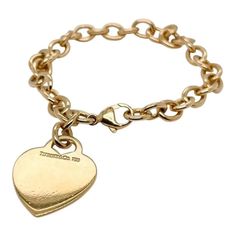 This is part of Chairish’s Fine Jewelry assortment. A very fine Tiffany Co. bracelet. In 18k gold. With slightly oval links and a heart-shaped pendant charm. The charm is not engraved. Simply wonderful, classic Tiffany design! Date: 20th Century Overall Condition: It is in overall good, as-pictured, used estate condition with some very fine light surface scratches and other signs of expected light wear consistent with age. Fineness: Marked 750 for 18k gold fineness. Marks: Tiffany Co. / Elegant Charm Bracelet With Logo Charm As Gift, Classic Gold-tone Charm Bracelet, Luxury Charm Bracelet With Logo, Elegant Gold Plated Jewelry With Logo Charm, Formal Yellow Gold Jewelry With Logo Charm, Classic Gold Heart Bracelet, Luxury Yellow Gold Charm Bracelet With Logo, Classic Formal Jewelry With Logo Charm, Classic Engraved Charm Bracelet For Formal Occasions