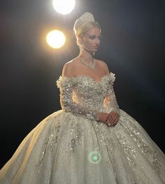 a woman in a ball gown is standing on the runway wearing a tiara and diamond jewelry