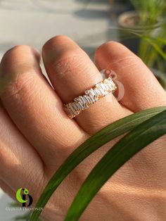 a woman's hand with a gold ring on top of it and grass in the background