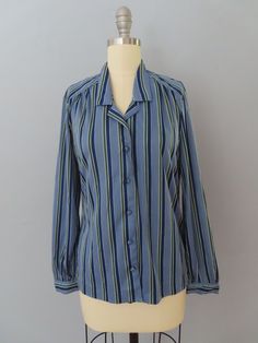 Vintage 70's long sleeve disco blouse. Super soft in medium blue with dark blue, white and green vertical stripes. Cutaway collar with button-up front. Fabric colored buttons. Slim fit style. Long sleeves with button cuffs. Straight hem. Fits a modern day women's size large. Please see measurements below. MEASUREMENTS--Taken with garment laying flat, in inches, doubled: Chest: 42"  Waist: 36"  Shoulder: 16" Sleeves: 23" Length: 24" Label/ Era: Panther| 1970 Fabric: Polyester, fabric covered buttons Condition: Excellent condition. Freshly laundered and no known issues. ★ Shop the entire shop here: https://www.etsy.com/shop/retrosuzysvintage Instagram | retrosuzysvintage Facebook | retrosuzysvintage Pinterest | retrosuzysvintage Fitted Vertical Stripes Top For Fall, Fitted Tops With Vertical Stripes For Fall, Collared Tops With Vertical Stripes For Fall, Blue Long Sleeve Blouse With Vertical Stripes, Blue Fitted Tops With Vertical Stripes, Fitted Blue Tops With Vertical Stripes, Blue Fitted Top With Vertical Stripes, Fitted Blue Top With Vertical Stripes, Spring Long Sleeve Blouse With Vertical Stripes