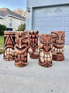 four wooden tiki mugs sitting in front of a garage door