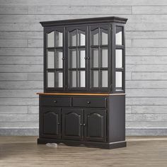 a black china cabinet sitting on top of a hard wood floor next to a wall