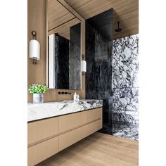 a bathroom with marble counter tops and wooden cabinets, along with a large mirror on the wall