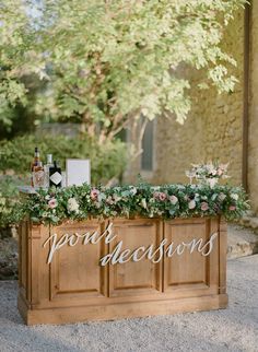 an outdoor bar with flowers and greenery on top