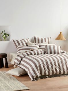 a bed with white and brown striped comforter in a room next to a rug