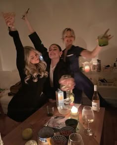 three women are posing for the camera with their arms in the air while holding drinks