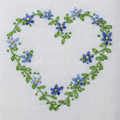 a heart shaped embroidered with blue flowers and green leaves