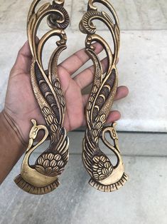 two brass swan figurines sitting on top of a marble floor next to each other