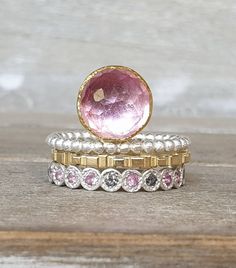 A gorgeous set of rings, you can buy them separate or as a set. We have a central ring with a pink topaz wrapped in a 22k bezel set aside with my silver dot band. Then my cube 14k gold band and my silver half infinity diamond and pink sapphire band. The combo is so unique, you can play with those rings so much. A pastel set to feel unique. Made to order, size 7, can be resized. Pink Sapphire Band, Pink Topaz Ring, 22k Gold Ring, Gemstone Stacking Ring, Tanzanite Jewelry, Multi Gemstone Ring, Sparkly Ring, Rose Gold Bangle, Sapphire Band