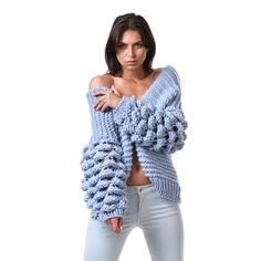 a woman posing with her arms crossed and wearing a blue knitted sweater over her shoulders