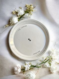 a white plate sitting on top of a table covered in flowers and writing that says, i love you