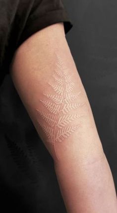 a person with a tattoo on their arm that is white and has an intricate design