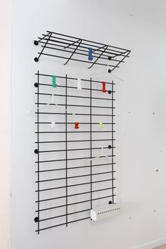 a white wall with several pieces of art hanging on it's sides and various colored pegs attached to the wall