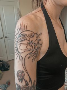 a woman with a tattoo on her arm and shoulder, standing in front of a mirror