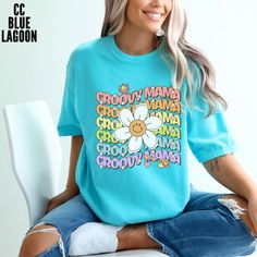 Groovy Mama Stacked Rainbow Butterfly and Daisy Comfort Colors Shirt Embrace your inner groovy mama with this fun and colorful stacked design on a comfort colors shirt! Each letter pops in alternating rainbow colors, surrounded by playful butterflies and centered with a big smiling daisy. This shirt is sure to spread positive vibes and stand out in style wherever you go. Perfect for those who love a retro, cheerful look that radiates happiness and good energy. Add a pop of color and sunshine to Funny Blue Graphic Print T-shirt, Funny Letter Print Tops For Fans, Funny Blue T-shirt For Summer, Graphic Print T-shirt For Spring Fan Apparel, Funny Print Crew Neck Top For Fans, Cotton Tops With Funny Print For Fans, Funny Blue T-shirt With Text Print, Spring Fan Merchandise T-shirt, Funny Blue T-shirt With Graphic Print