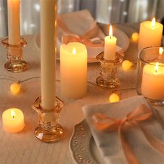 candles are lit on a table with plates and napkins