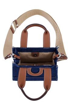 Contrast topstitching and the iconic winged logo bring a familiar finish to a squared denim tote bag topped with a trio of handles for convenient carrying. 8" H x 7" W x 4" D 5" handle drop, 25" strap drop Dual top handles, optional crossbody strap Textile and synthetic Lined Imported Rectangular Denim Blue Bag For On-the-go, Denim Blue Shopping Bag With Double Handle, Denim Blue Double Handle Shopping Bag, Shopping Bag With Double Handle In Denim Blue, Denim Tote Bag With Top Carry Handle, Denim Bags With Top Carry Handle For Daily Use, Daily Use Denim Bags With Top Carry Handle, Denim Blue Leather Rectangular Bag, Rectangular Denim Blue Leather Bag