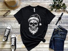 Gothiccore Skull Wearing Santa Hat Shirt, Cool Christmas Graphic Tee, Skeleton Holiday Party Shirt, Gothic Xmas T-Shirt, Metal Lover Apparel, Unisex Description Embrace your Gothic style this holiday season with this edgy skull wearing a Santa hat shirt 🎅💀. Perfect for Christmas parties, music festivals, or just showing off your love for the darker side of the holidays, this unique tee combines festive cheer with a Gothic twist. High-quality fabric for long-lasting comfort and durability Bold, Casual Halloween Holiday Tops, Black Christmas Streetwear T-shirt, Black T-shirt For Christmas Streetwear, Black Festive Streetwear T-shirt, Christmas Crew Neck Streetwear T-shirt, Christmas Streetwear Crew Neck T-shirt, Christmas Crew Neck T-shirt For Streetwear, Christmas Streetwear Cotton T-shirt, Christmas Cotton T-shirt For Streetwear