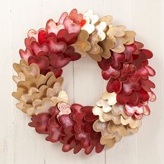 a red and gold wreath hanging on a white wooden wall next to a brick fire hydrant