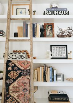 a book shelf with books and an old wooden ladder in front of white shelving