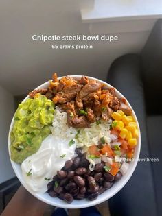 a white bowl filled with beans, rice and other food on top of a table