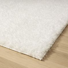 a white rug is laying on the floor with a wooden floor in front of it